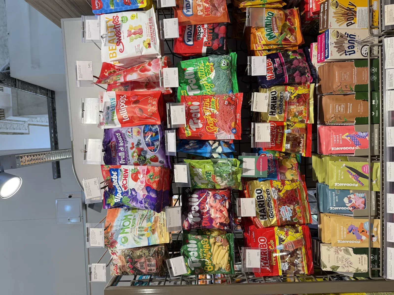 Surtido de gomitas en un estante de la CEI — los formatos escarchados destacan en paredes abiertas